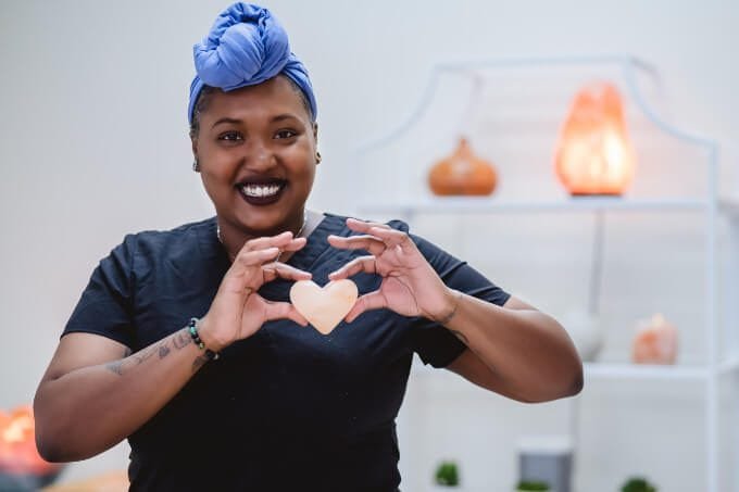 A therapist smling towards the camera while holding a heart stone