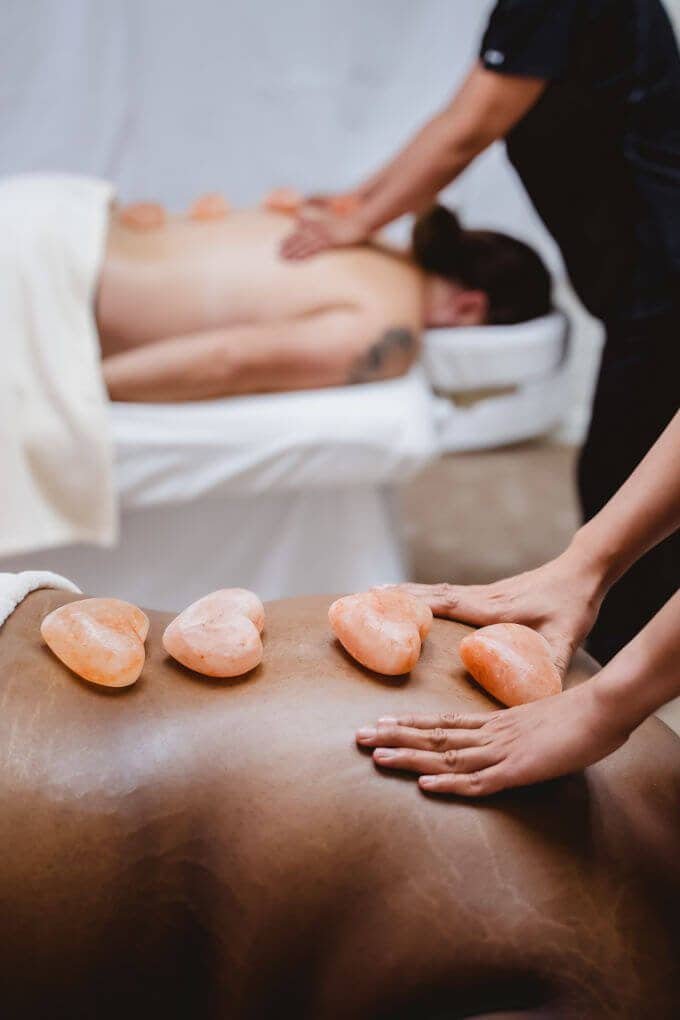 A therapist performing a hot stone massage on a client