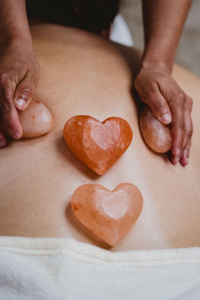 A therapist perfoming a heart stone massage on a client.