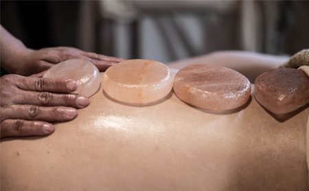 Image of Himalayan salt stones being placed on a client's back.