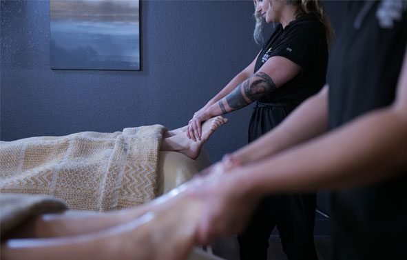 Relax-htto A therapist performing a foot massage during a couple's treatment.